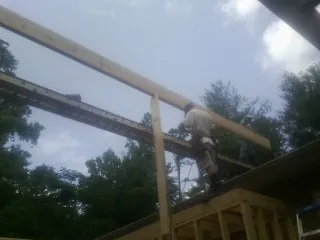 Carpenter setting a ridge beam over a new addition frame — Ice Dam Removal by Roofing Brothers in Lake Butler