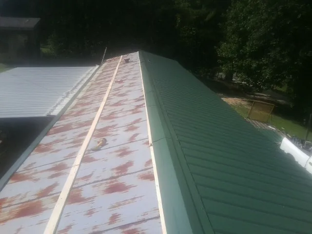 Old rusted panels beside newly installed green metal roofing — Wind Damage Roof Repair by Roofing Brothers in Lake Butler