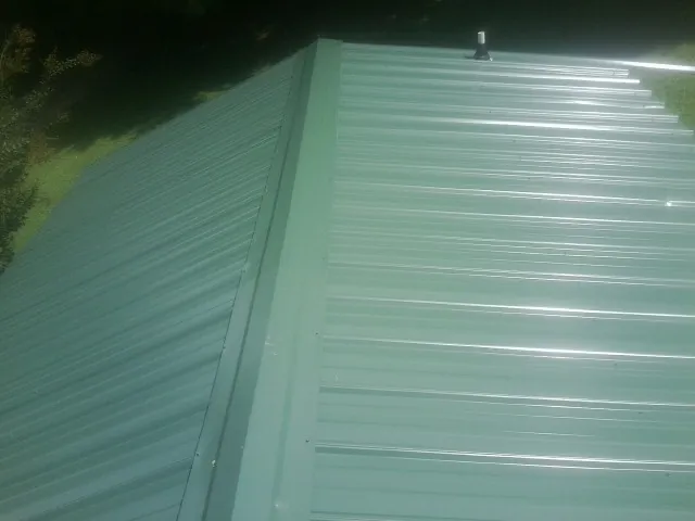 New green metal panels meeting at the ridge of a roof — Flat Roof Repair work by our crew in Lake Butler