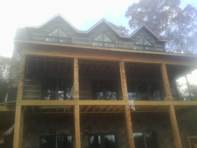 Dormers and porch framing on a large log home under construction — Roof Coating work by our crew in Lake Butler