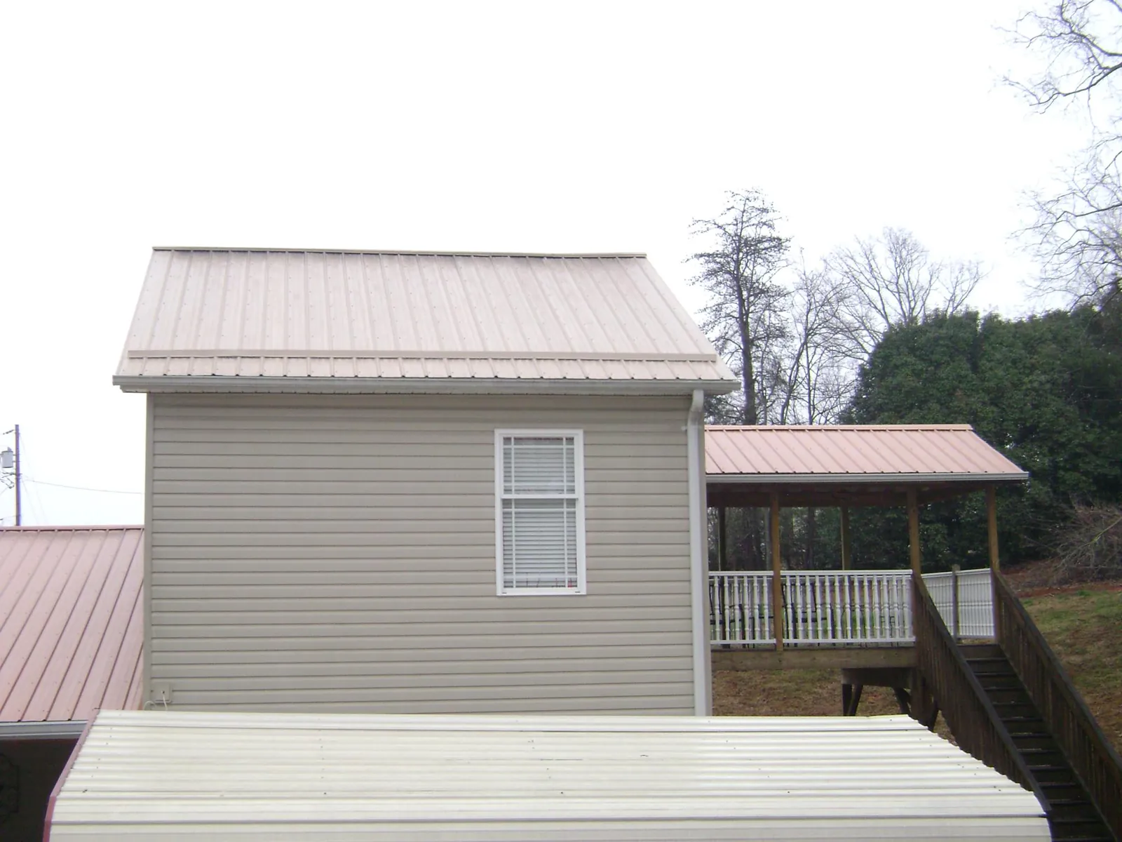Tan metal roofs on a two story addition and attached porch, from a Roof Replacement job in Lake Butler