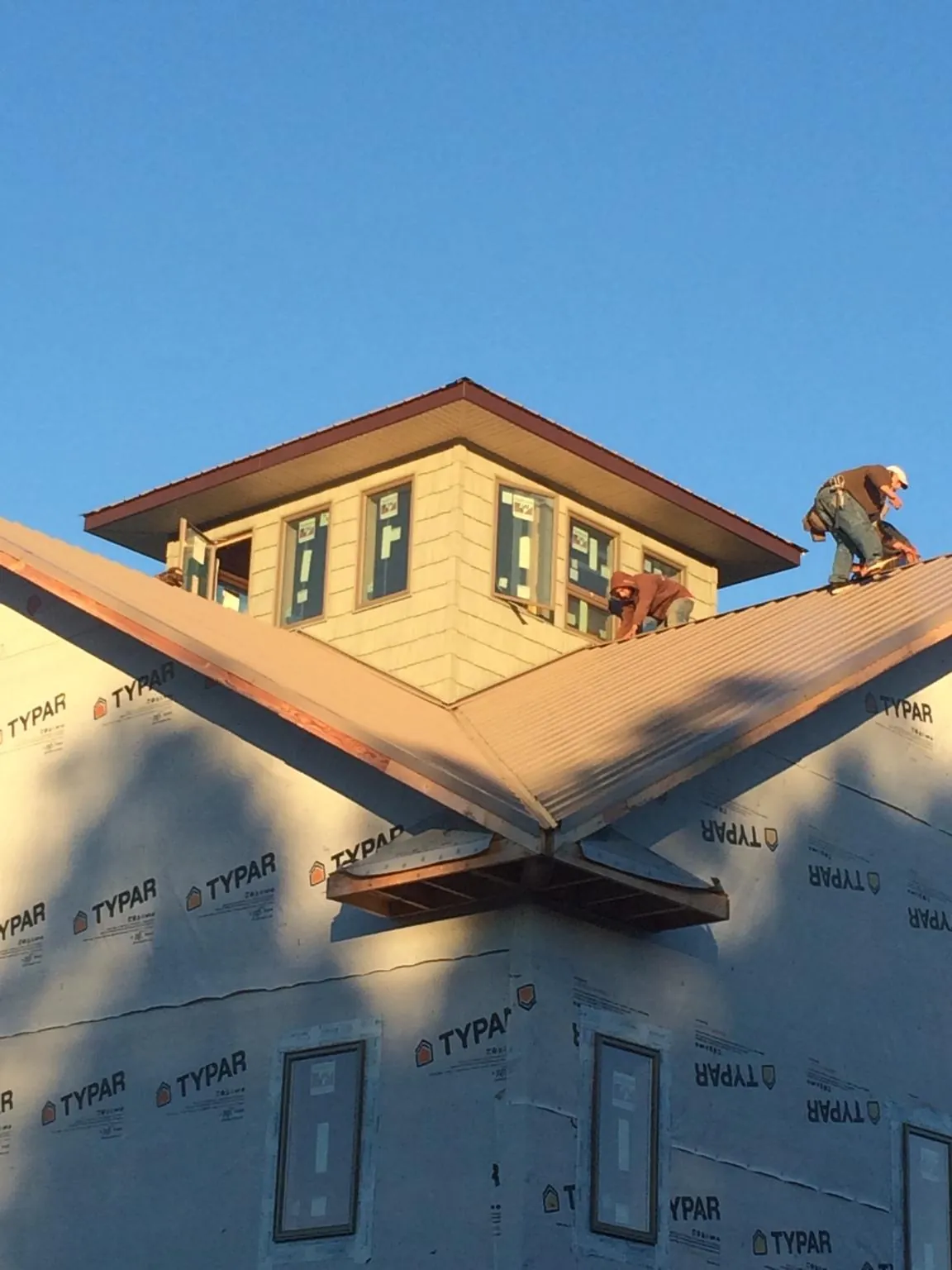 Roofers working around a rooftop cupola on a new metal roof at sunset — Roof Waterproofing in Lake Butler by Roofing Brothers